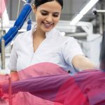 خانمی در حال نگهداری و مراقبت از دستگاه اتو پرس صنعتی برای افزایش طول عمر دستگاه