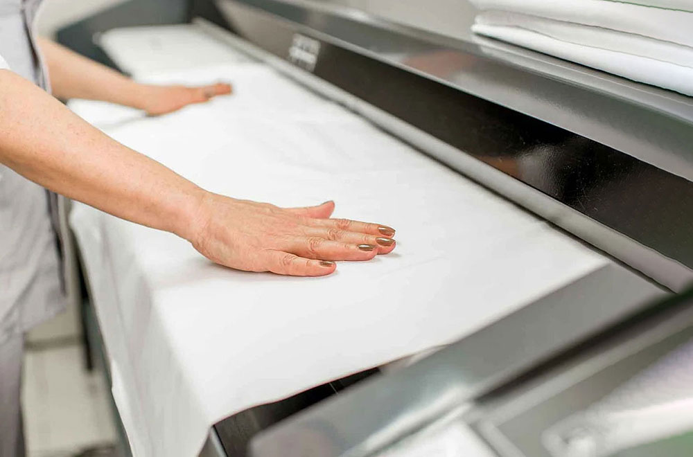 خانمی در حال اتوکشی با اتو غلطک صنعتی